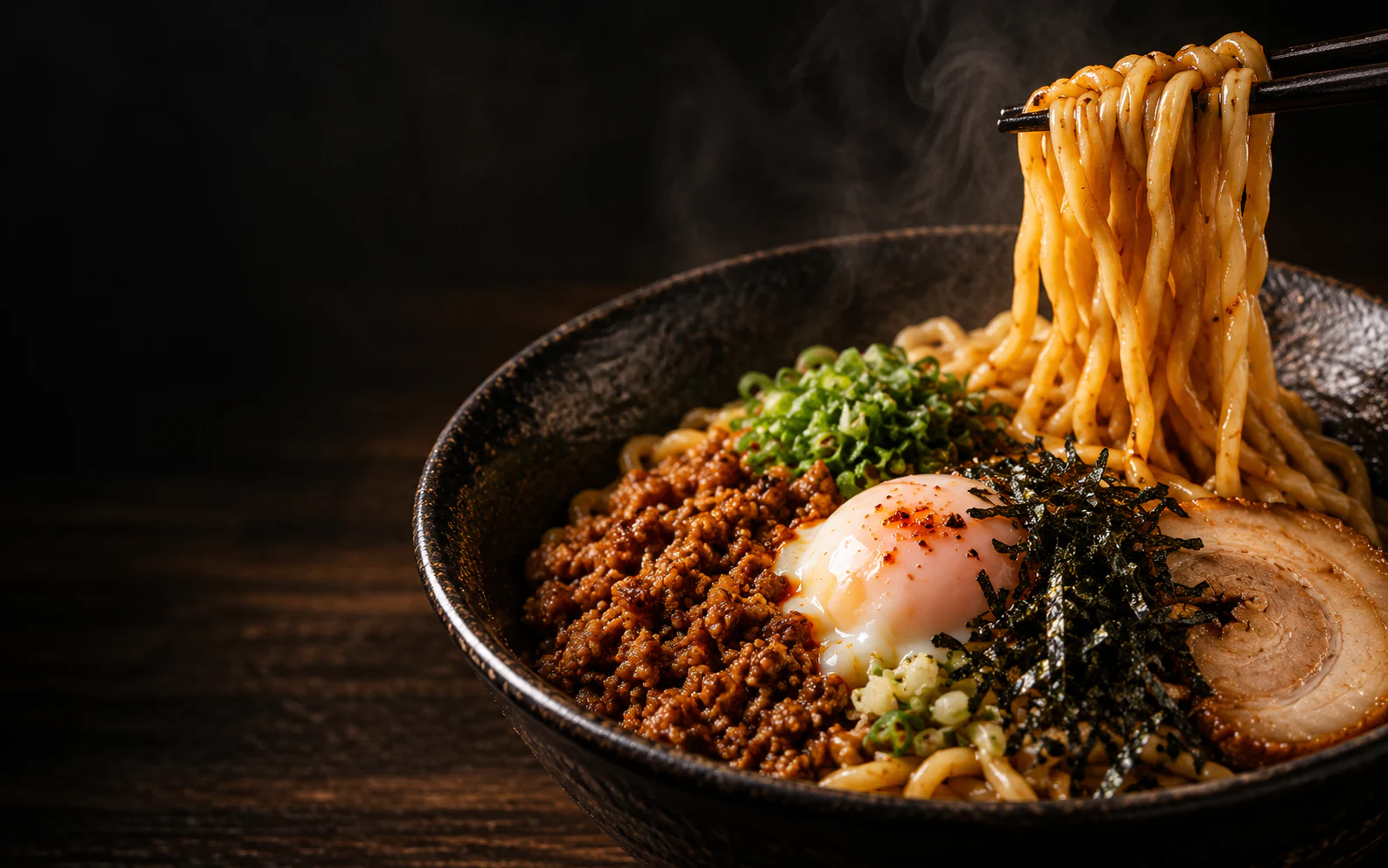 A bowl of abura soba with glossy noodles lifted by chopsticks